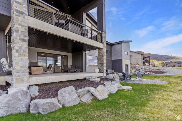 back of property with a balcony, a patio area, and a yard