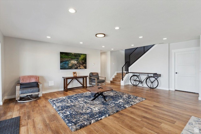 sitting room with stairs, wood finished floors, baseboards, and recessed lighting