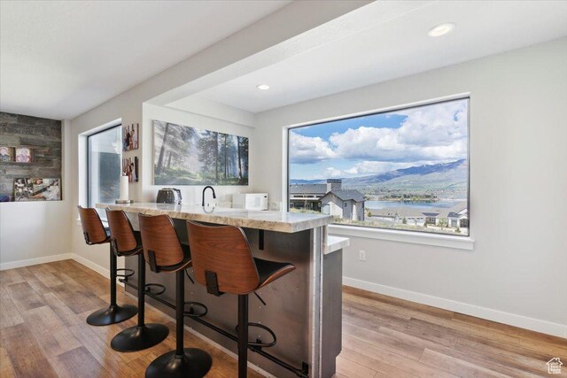 kitchen with light wood-style flooring, a breakfast bar area, baseboards, and recessed lighting