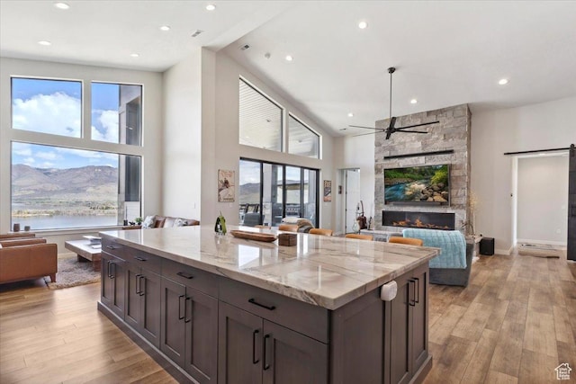 kitchen featuring open floor plan, a ceiling fan, light wood-style flooring, a high ceiling, and a kitchen island