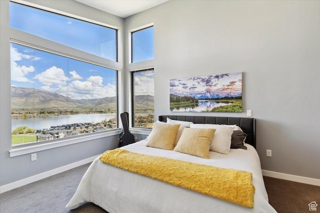 carpeted bedroom featuring a water view and baseboards