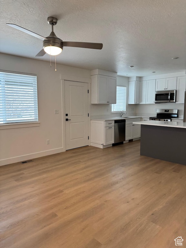 kitchen with appliances with stainless steel finishes, a sink, light countertops, baseboards, and a textured ceiling