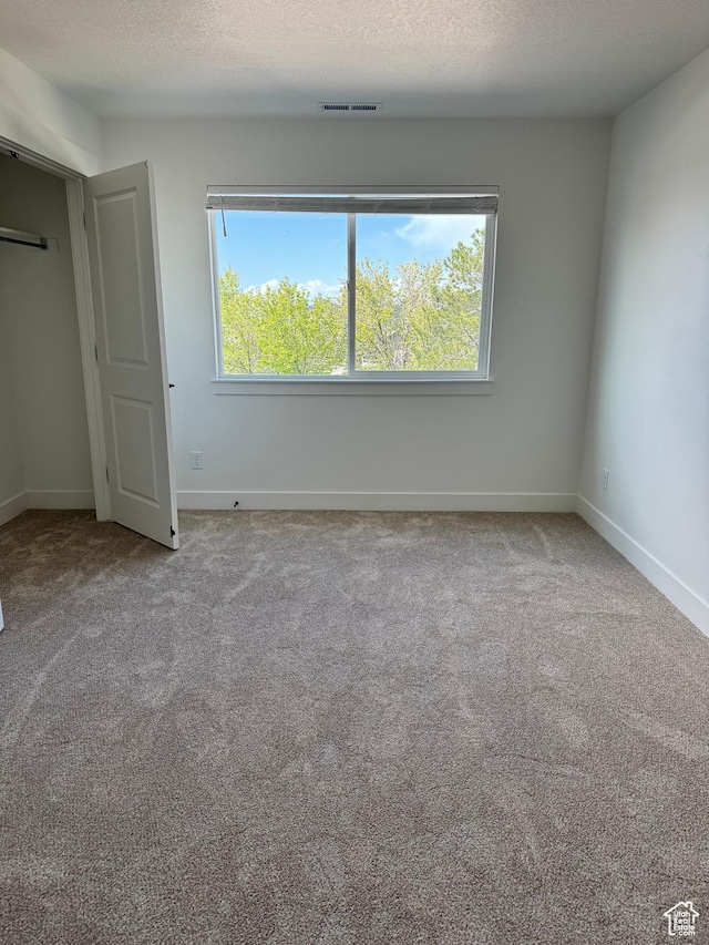 unfurnished bedroom with carpet, baseboards, and a textured ceiling