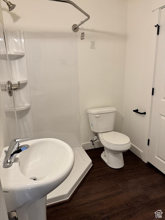 full bathroom featuring a shower, wood finished floors, a sink, toilet, and baseboards