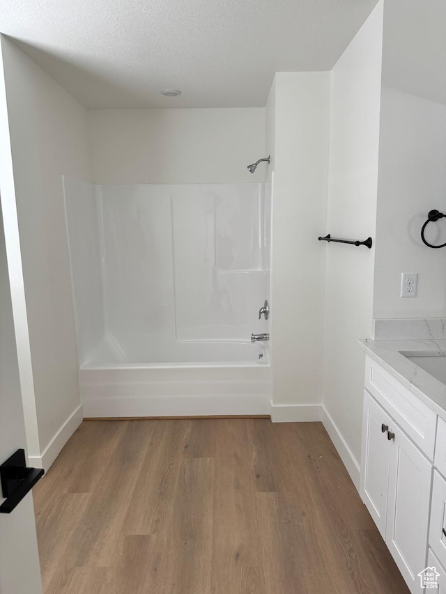 full bathroom with wood finished floors, shower / tub combination, baseboards, and vanity