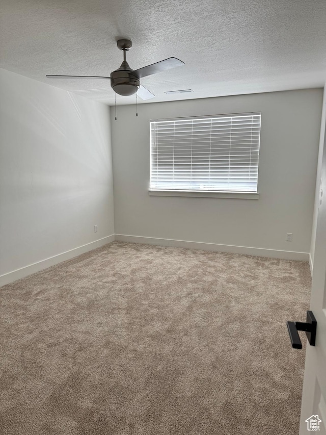carpeted empty room with ceiling fan, a textured ceiling, and baseboards