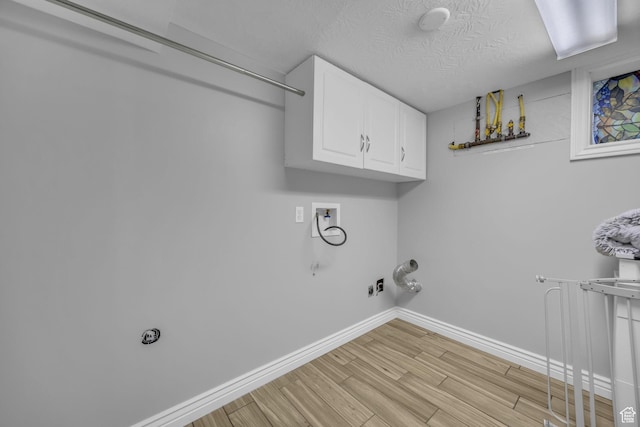 washroom with hookup for a gas dryer, cabinet space, baseboards, hookup for a washing machine, and light wood-style floors