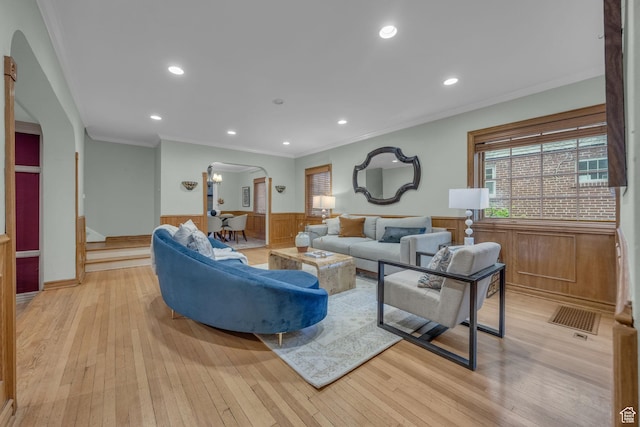 living room with arched walkways, a wainscoted wall, ornamental molding, light wood finished floors, and recessed lighting