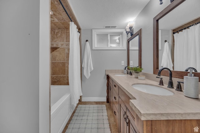 full bath featuring baseboards, double vanity, shower / tub combo, and a textured ceiling