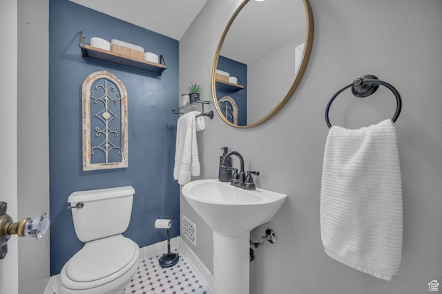 half bathroom with baseboards and toilet