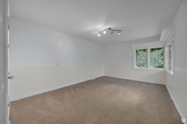 spare room featuring a wainscoted wall and carpet flooring