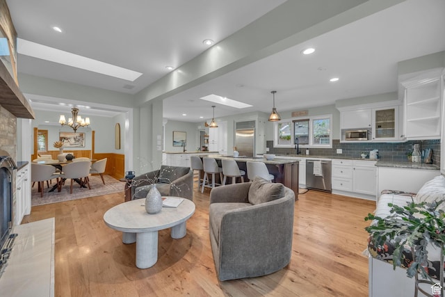 living area with light wood-type flooring, a chandelier, a skylight, and recessed lighting