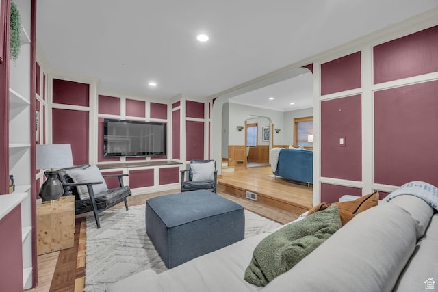 living area with arched walkways, recessed lighting, and wood finished floors