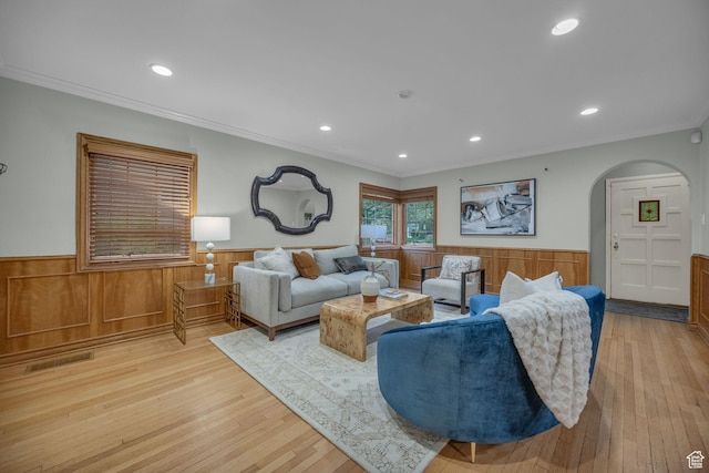 living area featuring a wainscoted wall, arched walkways, light wood-style floors, ornamental molding, and recessed lighting