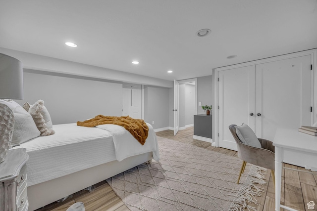 bedroom with light wood-style floors, recessed lighting, baseboards, and a closet