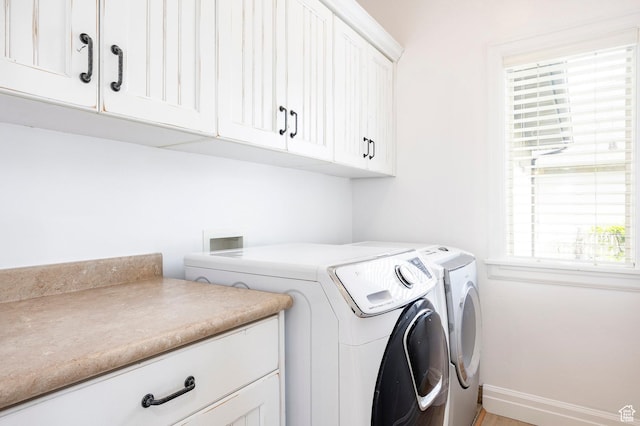laundry room with washing machine and dryer, cabinet space, and baseboards