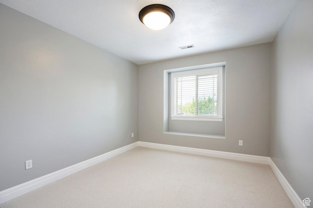 empty room featuring baseboards and light colored carpet