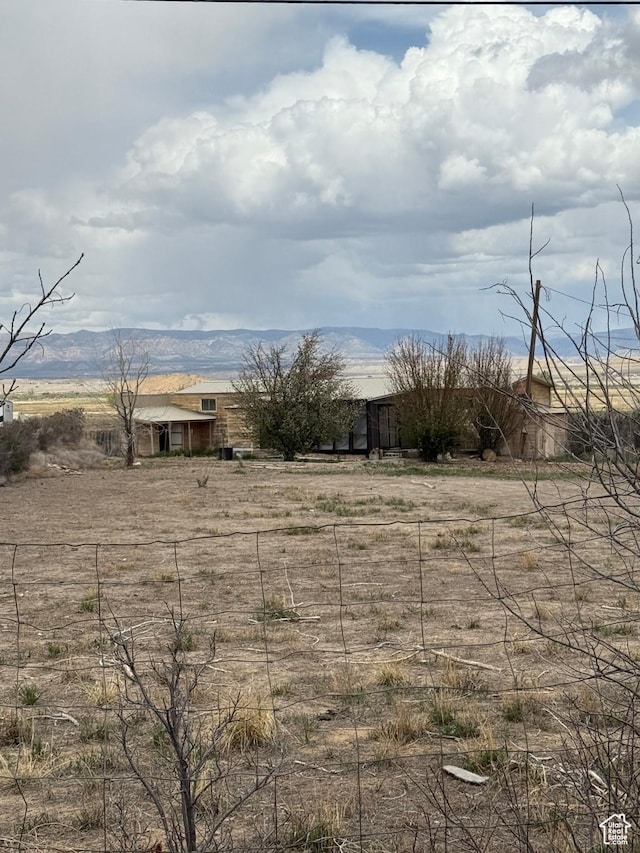 view of yard featuring fence, a rural view, and a mountain view