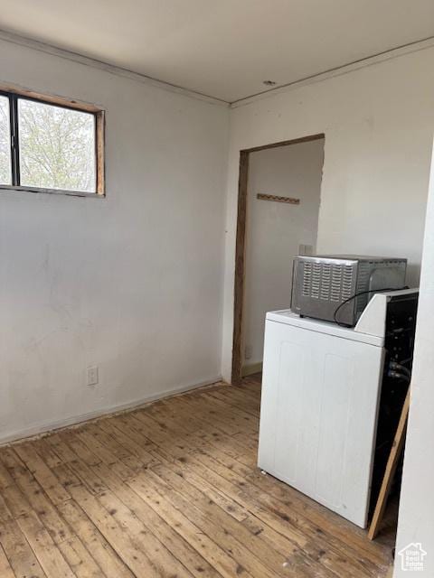 clothes washing area featuring washer / dryer, hardwood / wood-style flooring, and baseboards