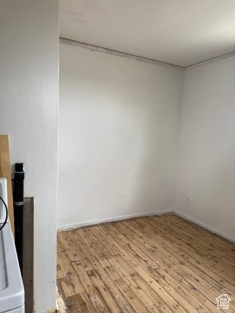 empty room featuring wood finished floors, baseboards, and washer / clothes dryer