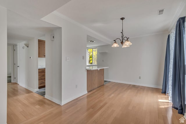 unfurnished room featuring a chandelier, light wood finished floors, baseboards, and crown molding