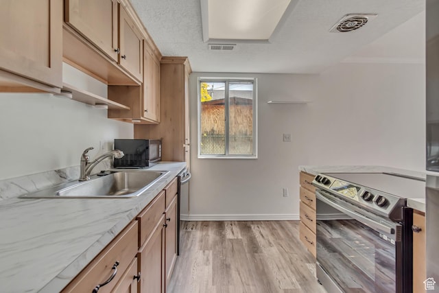 kitchen with appliances with stainless steel finishes, a sink, baseboards, light countertops, and light brown cabinets