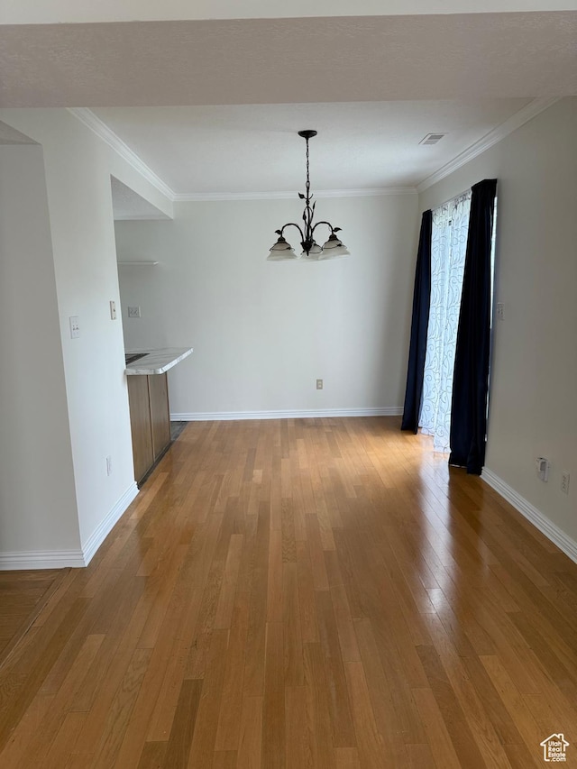 unfurnished dining area with a chandelier, light wood-style floors, ornamental molding, and baseboards