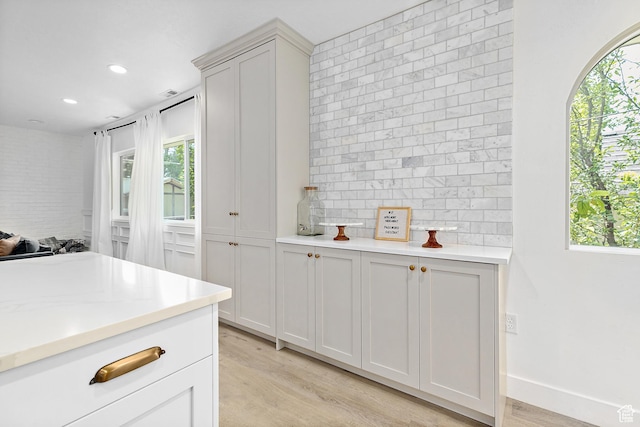 kitchen featuring healthy amount of natural light, light wood-style flooring, light countertops, recessed lighting, and tasteful backsplash