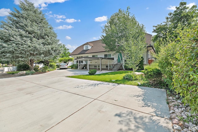 view of front facade featuring stairway, a front lawn, and concrete driveway