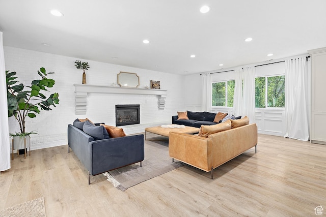 living room featuring light wood-style flooring, a brick fireplace, and recessed lighting