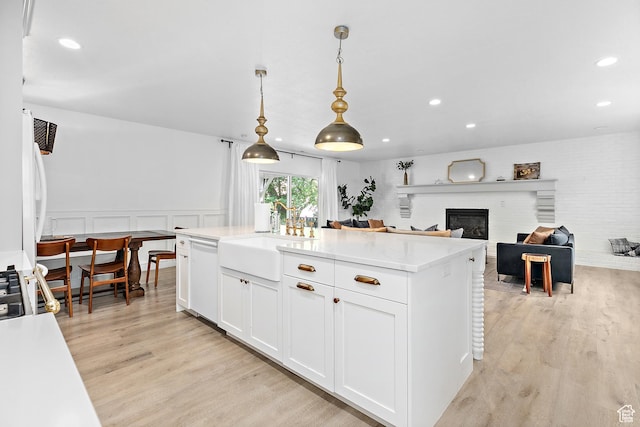 kitchen with light wood-style flooring, dishwasher, a sink, white cabinetry, and recessed lighting