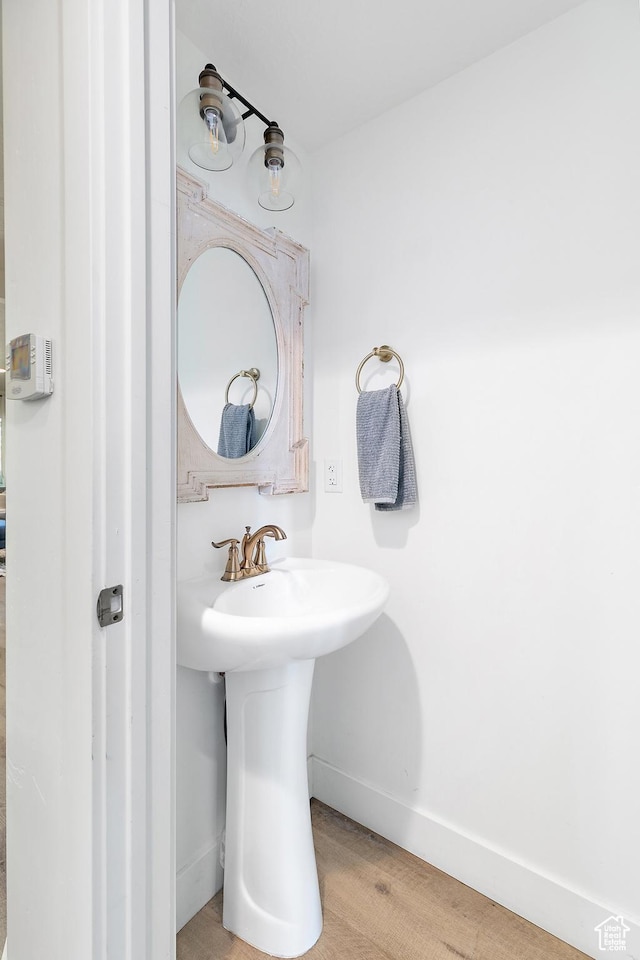 bathroom featuring baseboards, wood finished floors, and a sink