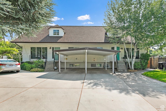 view of front of home featuring driveway, covered porch, a shingled roof, and stairway