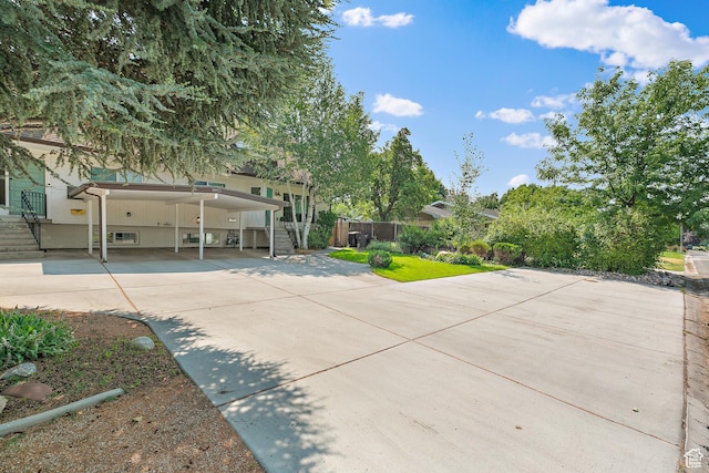 obstructed view of property with driveway, stairs, fence, and an attached carport