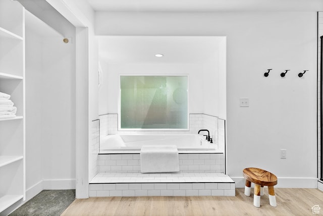 detailed view of a garden tub, baseboards, and wood finished floors