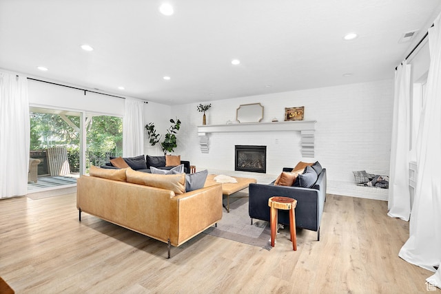 living room featuring light wood finished floors, recessed lighting, and a brick fireplace