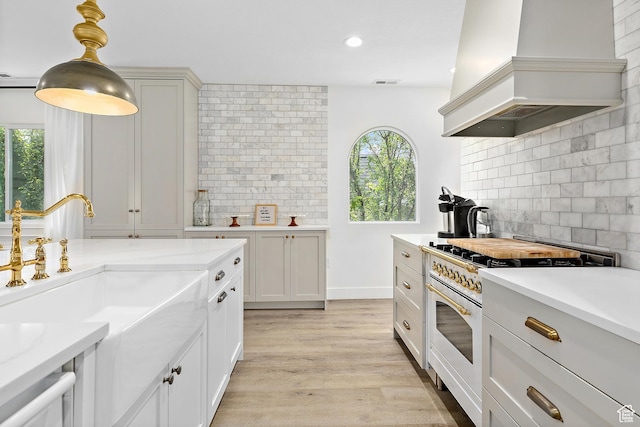 kitchen featuring gas stove, premium range hood, light countertops, backsplash, and recessed lighting