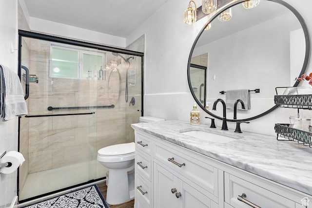 full bathroom with toilet, a shower stall, vanity, a chandelier, and tile walls