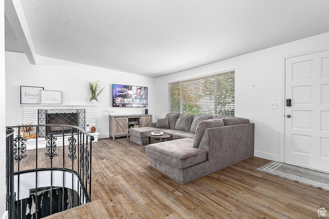 living area featuring wood finished floors, a brick fireplace, and baseboards