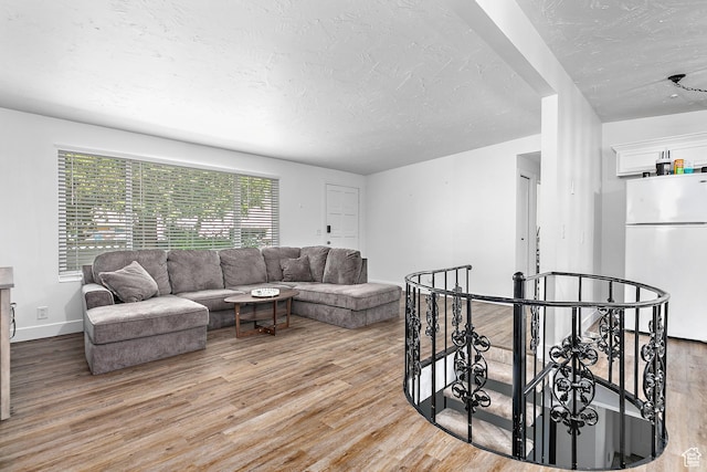 living room featuring a textured ceiling, light wood-type flooring, and baseboards
