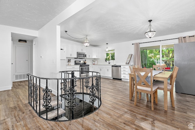 dining area featuring light wood finished floors, baseboards, and a textured ceiling