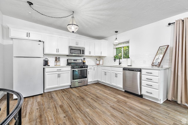 kitchen featuring appliances with stainless steel finishes, a sink, light wood-style flooring, light countertops, and a textured ceiling