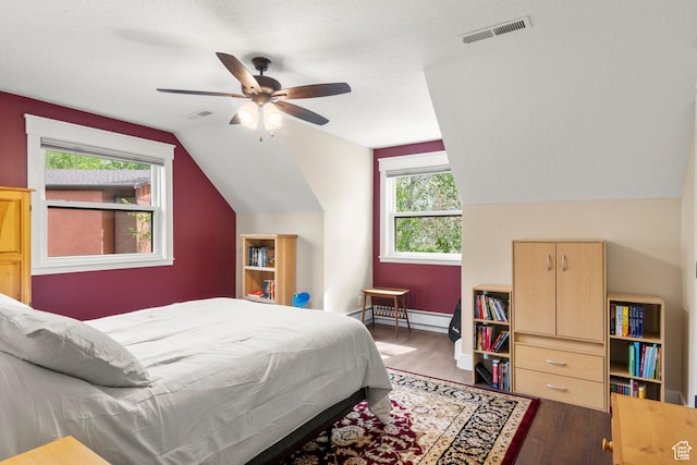 bedroom with wood finished floors, vaulted ceiling, ceiling fan, baseboards, and a baseboard heating unit