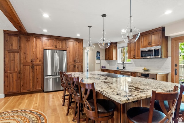 kitchen featuring appliances with stainless steel finishes, decorative backsplash, brown cabinets, recessed lighting, and light wood finished floors