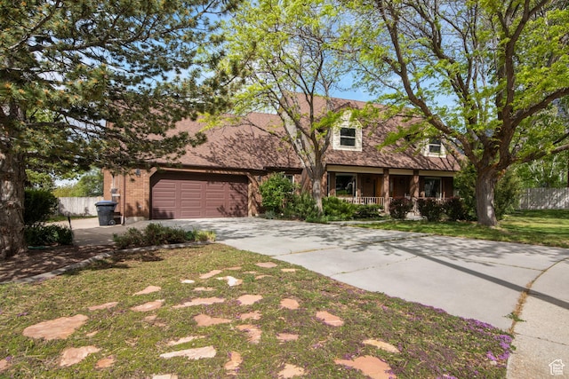 view of front facade with a porch, fence, concrete driveway, an attached garage, and brick siding