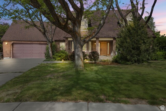 view of front of house with brick siding, concrete driveway, a garage, and a yard