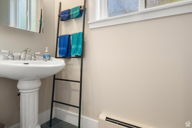 bathroom with a baseboard heating unit, baseboards, and a sink