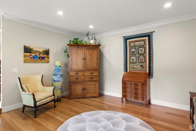 sitting room featuring light wood-type flooring, recessed lighting, baseboards, and crown molding