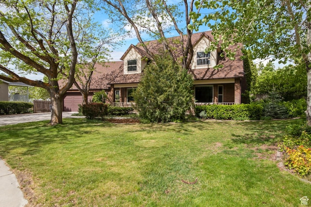 cape cod home with driveway, an attached garage, and covered porch