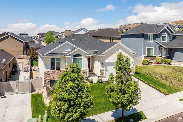 view of front facade with a gate, a residential view, stone siding, stucco siding, and driveway